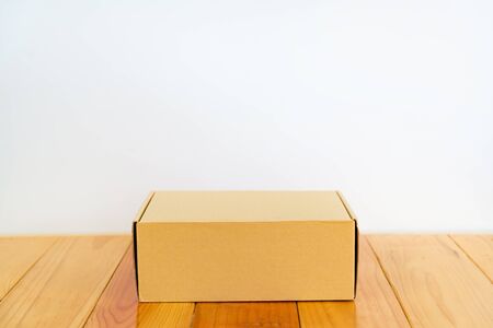 Empty brown cardboard box for mock up on bright wooden table with copy space.