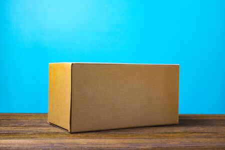 Empty closed brown cardboard box for mock up on dark wooden table with copy space.