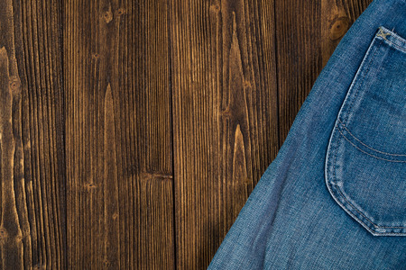 Frayed jeans or blue jeans denim collection on rough dark wooden table background, top view with copy space, old fashion style concept.の写真素材