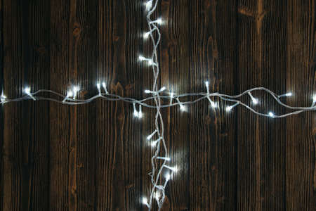 Fancy blinker light bulbs or garlands and wreath on wood table for Christmas or New years decoration background, space for add text or picture.の写真素材