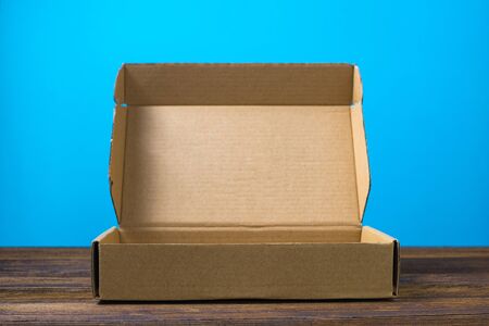 Empty closed brown cardboard box for mock up on dark wooden table with copy space.