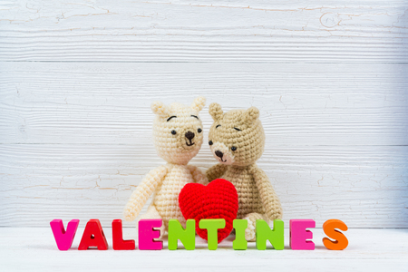 Sweet couple teddy bear doll in love with valentine text and red knitting heart on white wooden background and copy space for add text and picture, love and valentine day concept idea.の写真素材