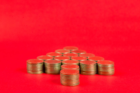 Stacks of coins arranged as a arrow or Christmas tree shape on red background, business metaphor...