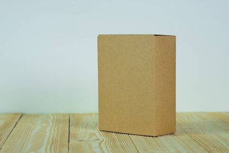Empty closed brown cardboard box for mock up on bright wooden table with copy space.