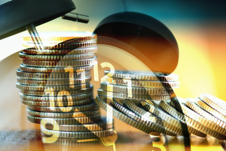 Double exposure stacks of coins on working table with alarm clock, finance and business concept idea.の写真素材