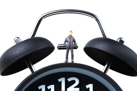Figure miniature businessman or small people standing with alarm clock, time for savings money concept or business financial idea.の写真素材