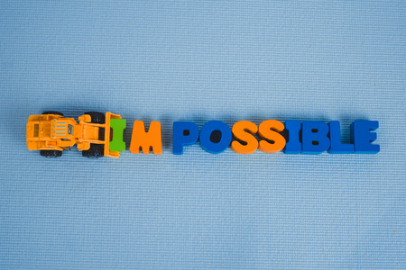 Mini bulldozer truck loading text IM changing impossible to possible text, business and finance concept idea.の写真素材