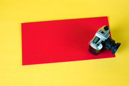 Mini camera toy and red envelop on yellow background with copy space for add text.