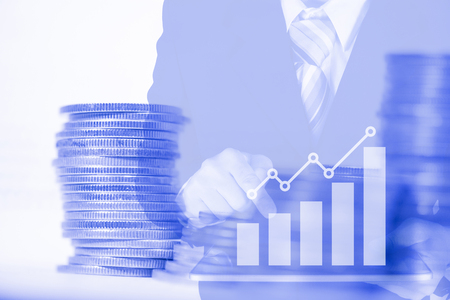 Double exposure businessman use tablet with financial graph and stacks of coins with copy space, finance and business finance concept idea.の写真素材