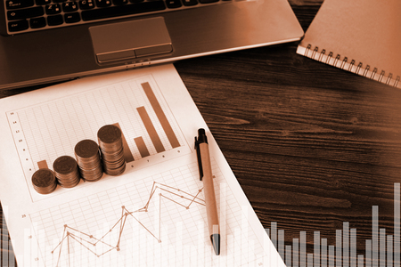 Step of coins stacks with notebook laptop computer and financial graph on white paper on working table, business planning vision and finance analysis concept idea. and copy space for add text.の写真素材