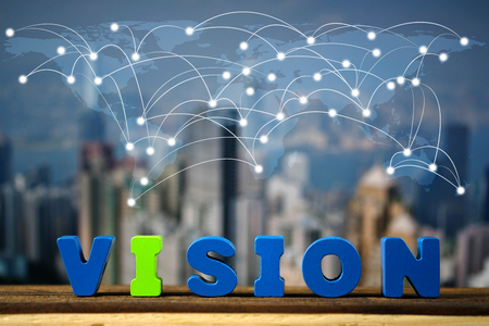 VISION text on top wooden working table with city background and world map,global network business...