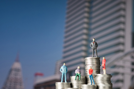 Figure miniature businessman of small people investor and office worker secretary standing on stack of coin, with modern city background for money and financial business success concept. shallow focus.の写真素材