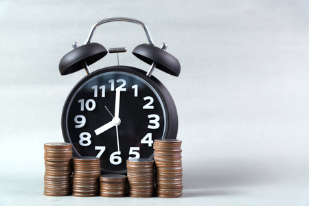 Alarm clock and step of coins stacks on working table, time for savings money concept, banking and...