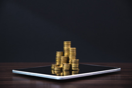 Coins stacks with tablet computer and financial graph, business planning vision and finance analysis...