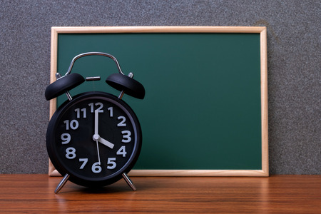 Black vintage alarm clock with green chalkboard, copy space for add your text, work on time or over time and deadline concept idea.の写真素材