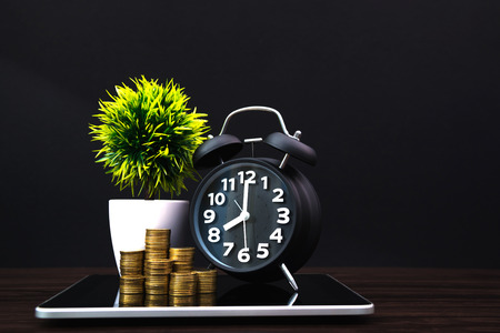 Coins stacks and alarm clock with tablet computer and financial graph, business planning vision and...