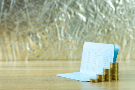 Step of coin stack with passbook or account book on wooden working table, savings and banking...