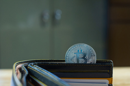 Bitcoin digital currency instead real money, bit-coin with leather wallet or purse on wooden working...