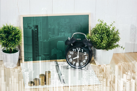 Double exposure coins stacks and alarm clock with green chalkboard, notebook and financial graph on city background, business planning vision and finance analysis concept idea.の写真素材