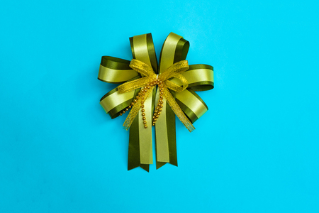 Decorative green ribbon bow on blue background, view from above with copy space for add text, template for festival or promotion and special day concept idea.の写真素材