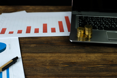 Step of coins stacks with notebook laptop computer and financial graph on white paper on working table, business planning vision and finance analysis concept idea. and copy space for add text.の写真素材