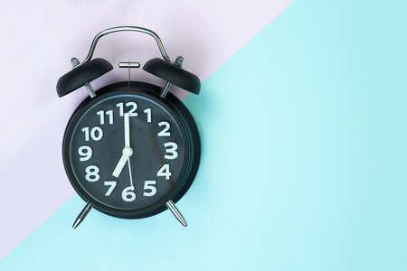 Flat lay vintage alarm clock on sweet pastel colored paper top view, background texture, pink, purple, yellow, beige, green and blue colour.の写真素材