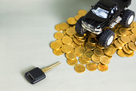 Car key and black colour of miniature car pickup truck on stacks of coins on grey background with copy space, banking savings money and business finance concept.の写真素材