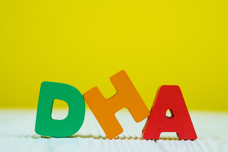 DHA text alphabet on white wooden table. yellow wall background with copy space for add text.の写真素材