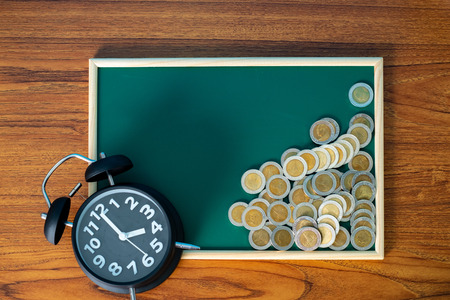Alarm clock and step of coins stacks on working table, time for savings money concept, banking and business idea.の写真素材
