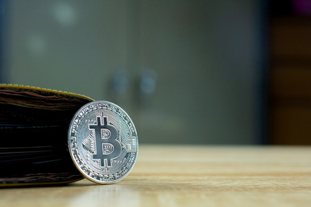 Bitcoin digital currency instead real money, bit-coin with leather wallet or purse on wooden working table, virtual cryptocurrency money business concept idea.の写真素材