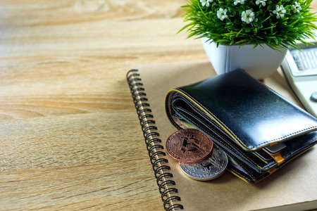 Bitcoin digital currency instead real money, bit-coin with leather wallet or purse on wooden working...