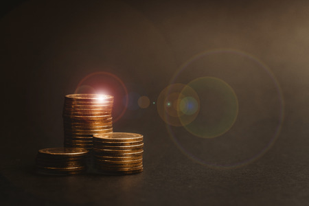 Savings, increasing columns of coins, piles of coins arranged as a graph in dark room, business...