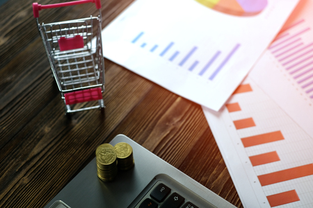 Step of coins stacks with trolley and notebook laptop computer and financial graph on paper on working table, business planning vision and finance analysis concept idea. and copy space for add text.の写真素材