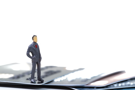 Figure miniature businessman or small people standing with stack of credit card on white background...