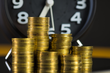 Coins stacks and alarm clock in dark room, business and finance concept idea.の写真素材