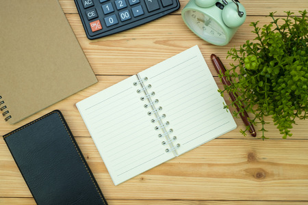 Office supplies or office work essential tools items on wooden desk in workplace, pen with notebook and calculator and alarm clock with copy space, top viewの写真素材