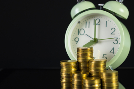 Coins stacks and alarm clock in dark room, business and finance concept idea.の写真素材