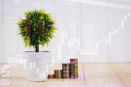 Double exposure of coin stack and little tree on city background with financial graph chart, business planning vision and finance analysis concept idea.の写真素材