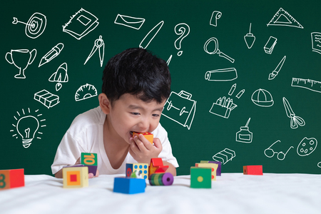 Asian kid learning by playing with his imagination about stationery supplies school object activities for learning, hand drawn on the green chalkboard, education back to school concept idea.の写真素材