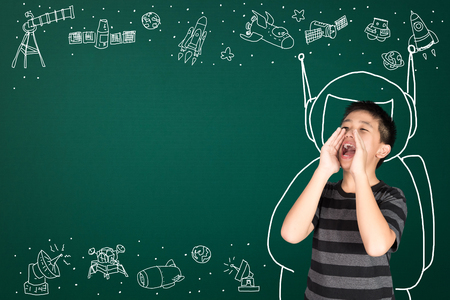 Asian kid with his imagination about science and space adventure, hand drawn on the green chalkboard, education back to school and discovery concept idea.の写真素材