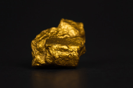 Closeup of gold nugget or gold ore on black background, precious stone or lump of golden stone, financial and business concept idea.の写真素材