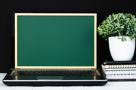 Notebook laptop computer with green chalkboard screen and pile of notebook paper stationery or school supplies. Back to school and education concept idea.の写真素材