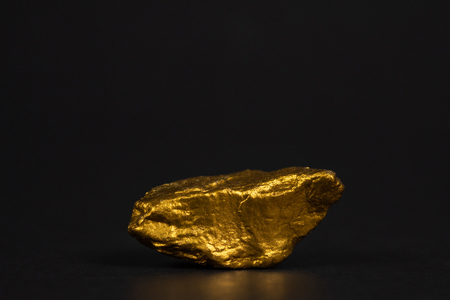 Closeup of gold nugget or gold ore on black background, precious stone or lump of golden stone, financial and business concept idea.の写真素材