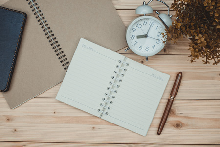 Office supplies or office work essential tools items on wooden desk in workplace, pen with notebook and alarm clock with copy space, top viewの写真素材