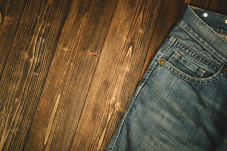 Frayed jeans or blue jeans denim collection on rough dark wooden table background, top view with copy space, old fashion style concept.の写真素材