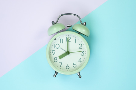 Flat lay vintage alarm clock on sweet pastel colored paper top view, background texture, pink, purple, yellow, beige, green and blue colour.の写真素材