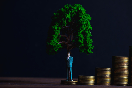 Figure miniature businessman or small people investor standing on coin stack with little tree decoration, for money and financial business success concept idea.の写真素材
