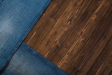 Frayed jeans or blue jeans denim collection on rough dark wooden table background, top view with copy space, old fashion style concept.の写真素材