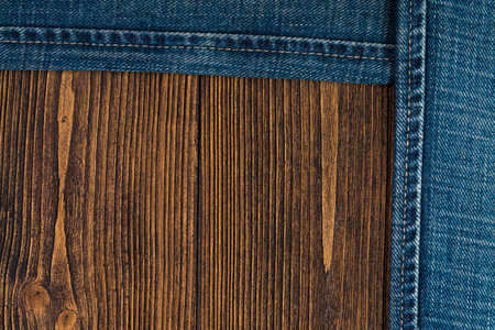 Frayed jeans or blue jeans denim collection on rough dark wooden table background, top view with copy space, old fashion style concept.の写真素材