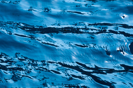 Blue and bright ripple clean water surface in swimming pool with sun reflection.の写真素材
